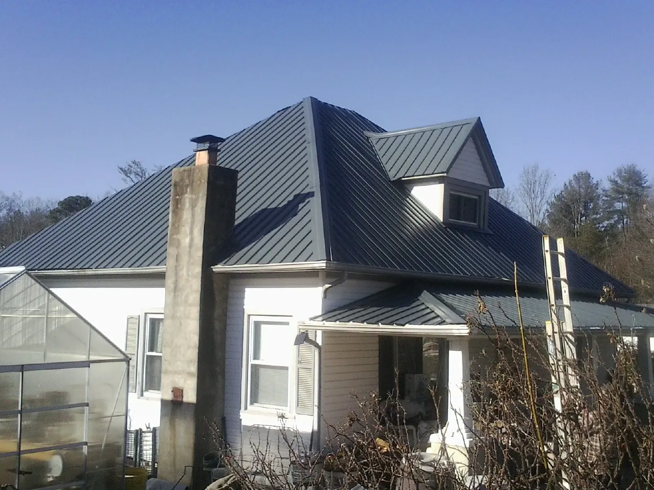 Dark blue standing seam metal roof on a white farmhouse with dormer — Slate & Tile Roof Repair by Roofing Brothers in Crocheron