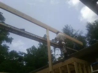 Carpenter setting a ridge beam over a new addition frame — Ice Dam Removal by Roofing Brothers in Crocheron