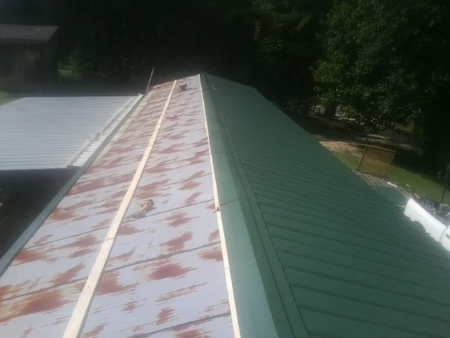 Old rusted panels beside newly installed green metal roofing — Wind Damage Roof Repair by Roofing Brothers in Crocheron
