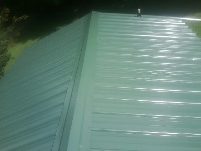 New green metal panels meeting at the ridge of a roof — Flat Roof Repair work by our crew in Crocheron