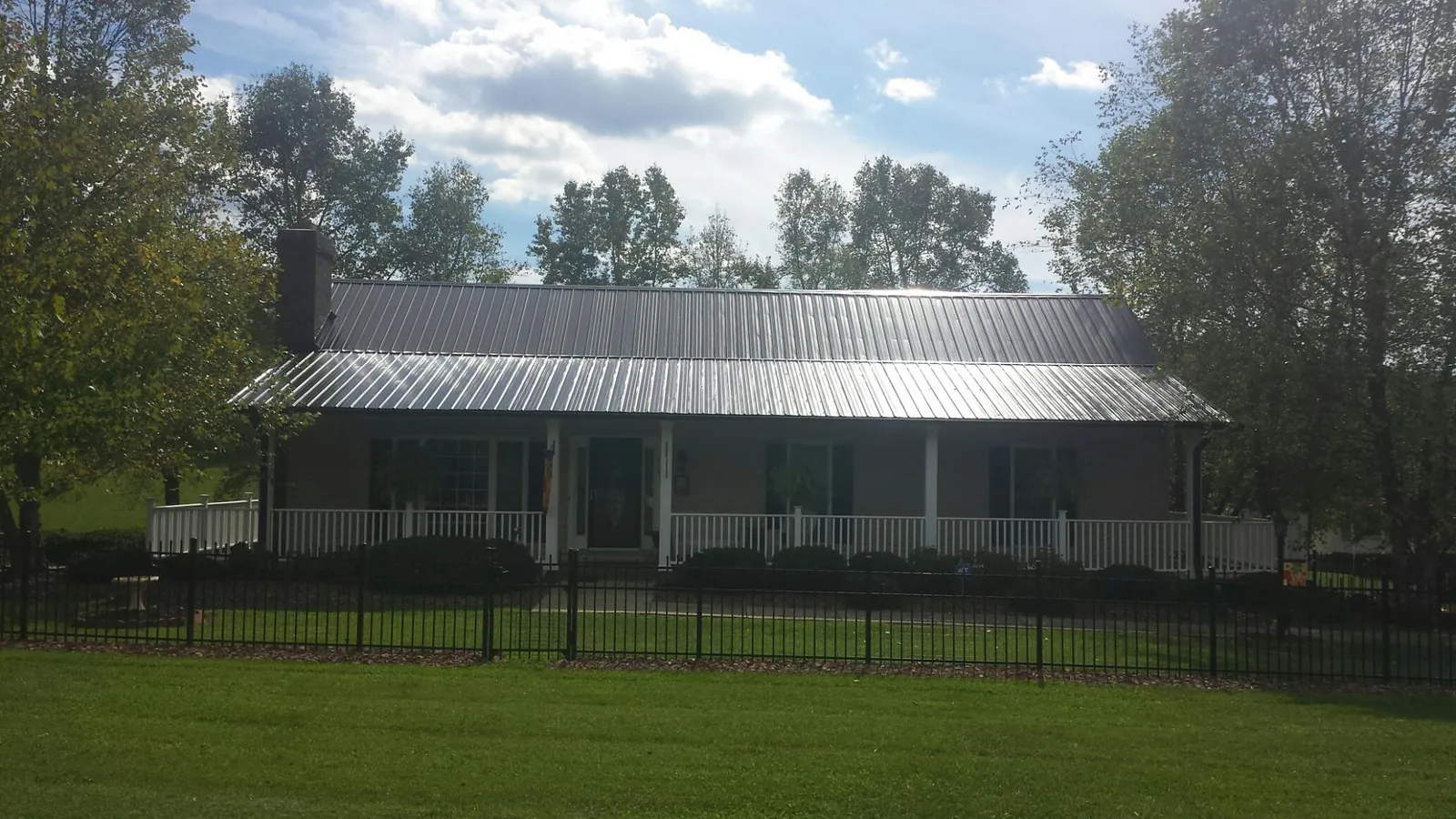 Gray metal roof on a brick ranch with a full width front porch — Gutter Guard Installation work by our crew in Crocheron