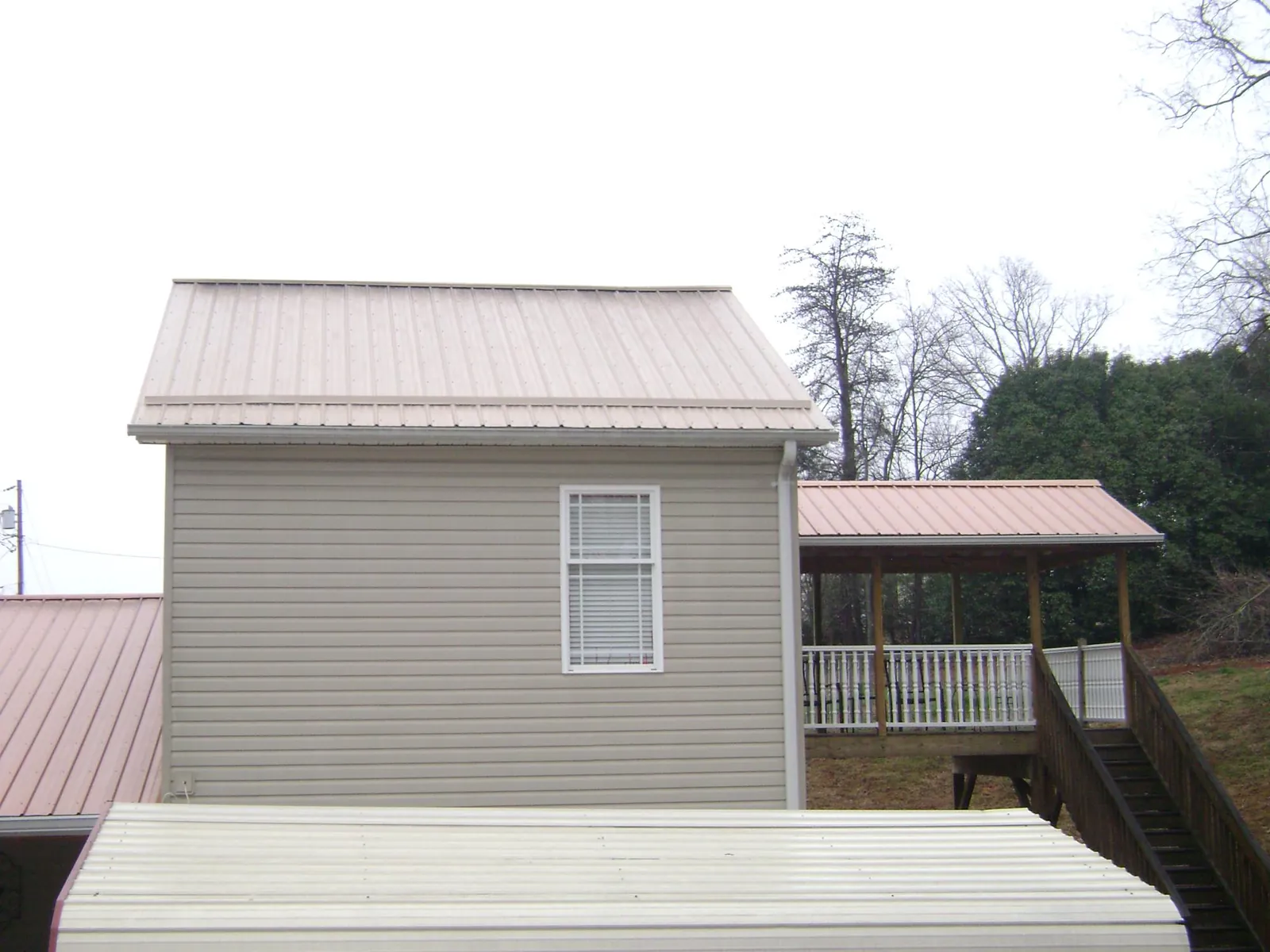 Tan metal roofs on a two story addition and attached porch, from a Roof Replacement job in Crocheron