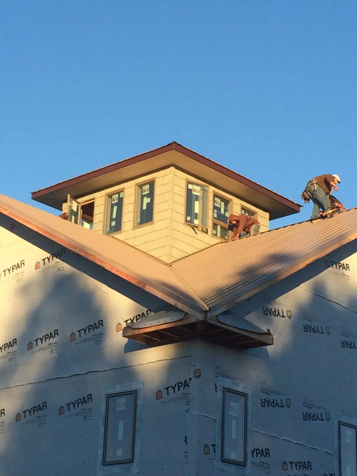Roofers working around a rooftop cupola on a new metal roof at sunset — Roof Waterproofing in Crocheron by Roofing Brothers